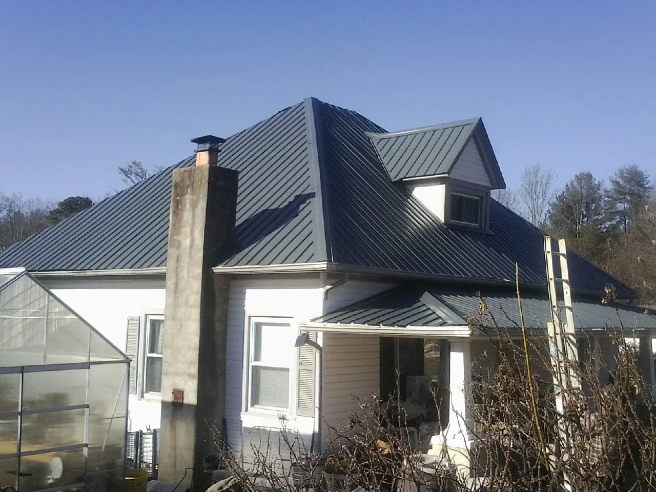 Dark blue standing seam metal roof on a white farmhouse with dormer — Slate & Tile Roof Repair by Roofing Brothers in Yarnell