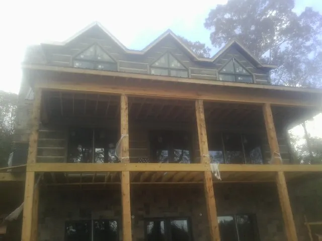 Dormers and porch framing on a large log home under construction — Roof Coating work by our crew in Yarnell