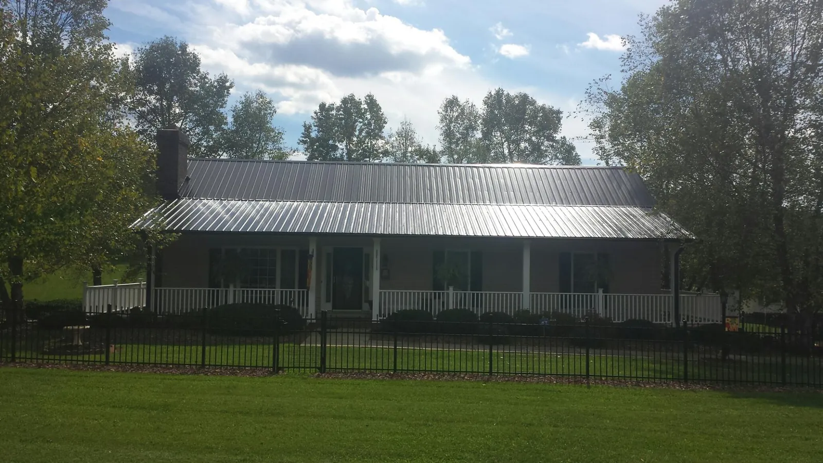 Gray metal roof on a brick ranch with a full width front porch — Gutter Guard Installation work by our crew in Yarnell