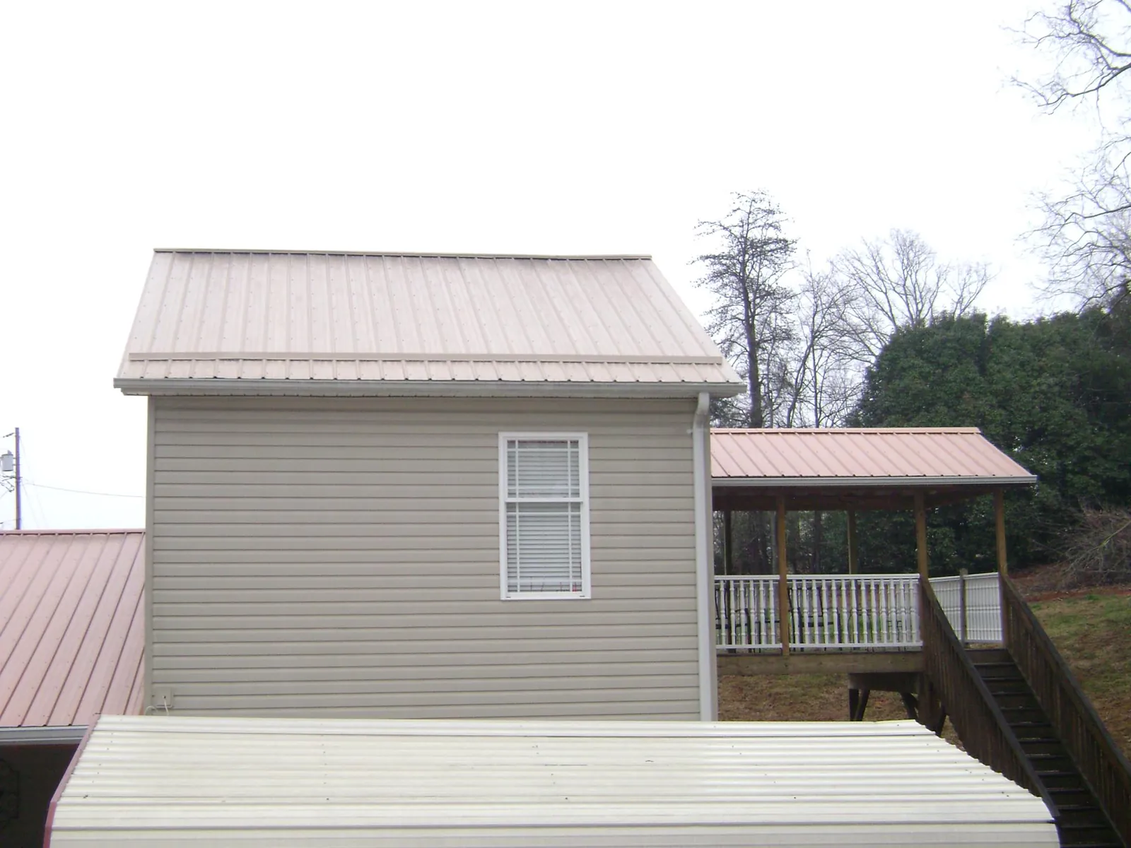 Tan metal roofs on a two story addition and attached porch, from a Roof Replacement job in Yarnell