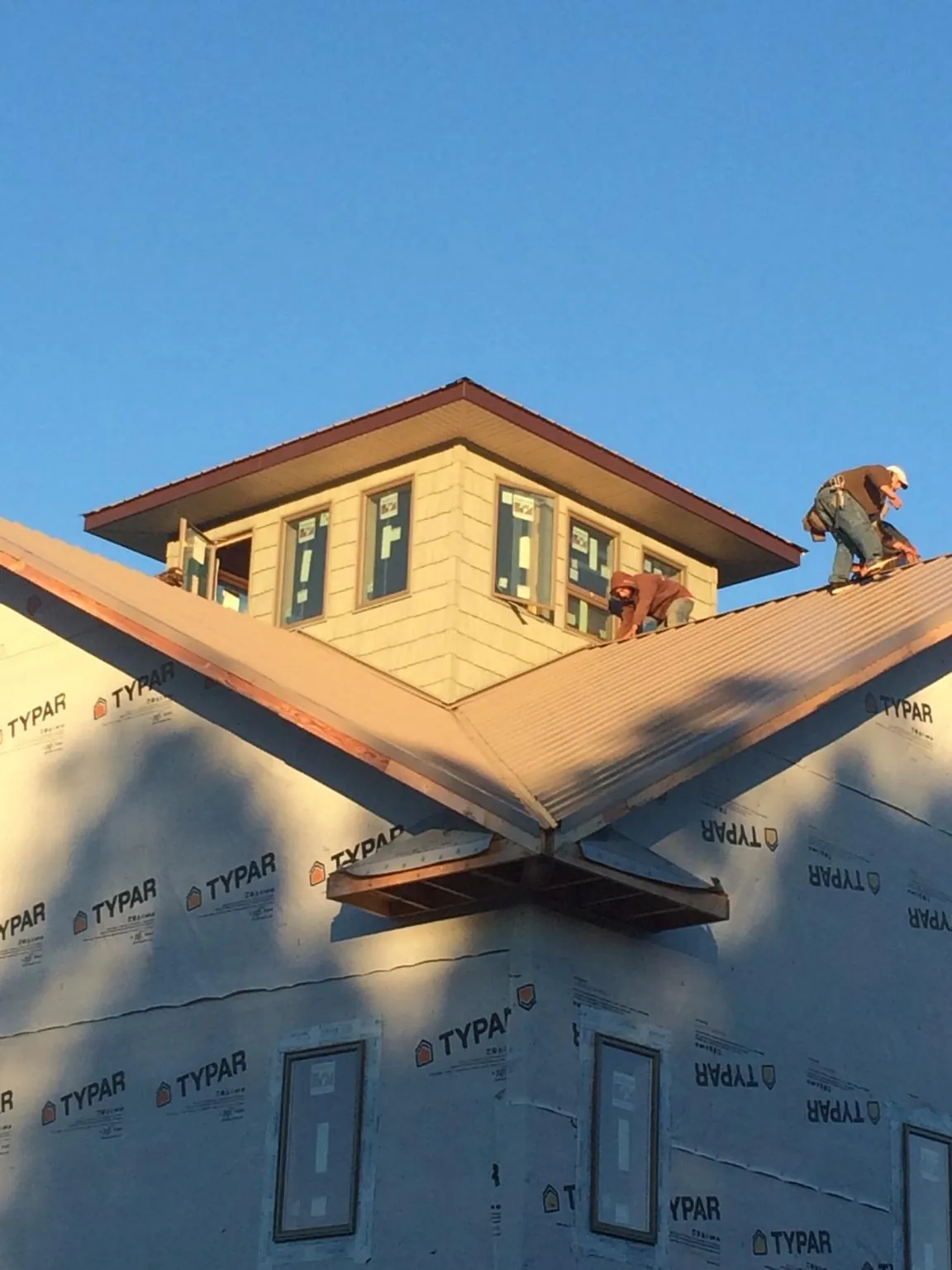 Roofers working around a rooftop cupola on a new metal roof at sunset — Roof Waterproofing in Yarnell by Roofing Brothers